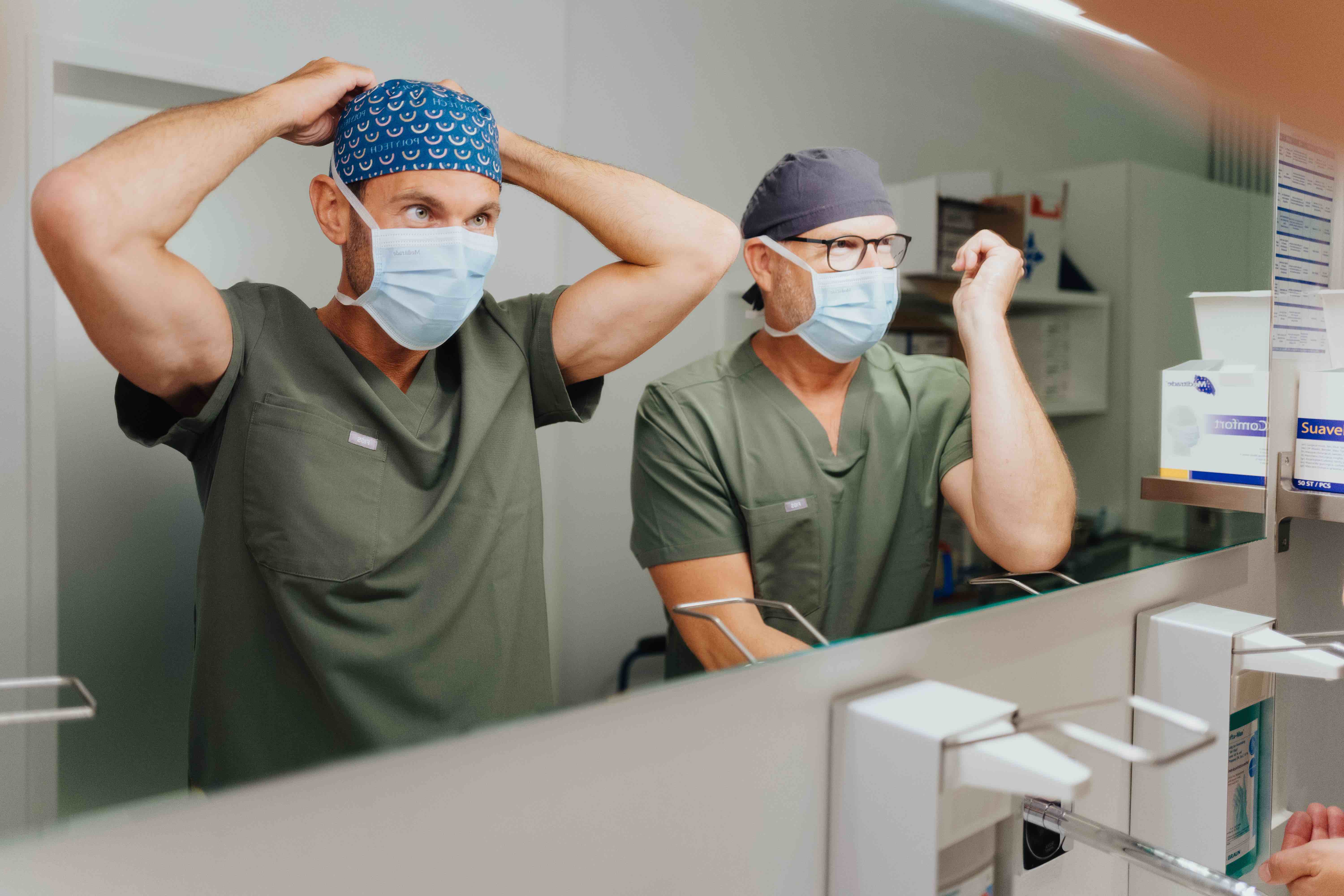 Dr. Bergmann und Dr. Kruess bereiten sich auf eine bevorstehende Operation vor.
