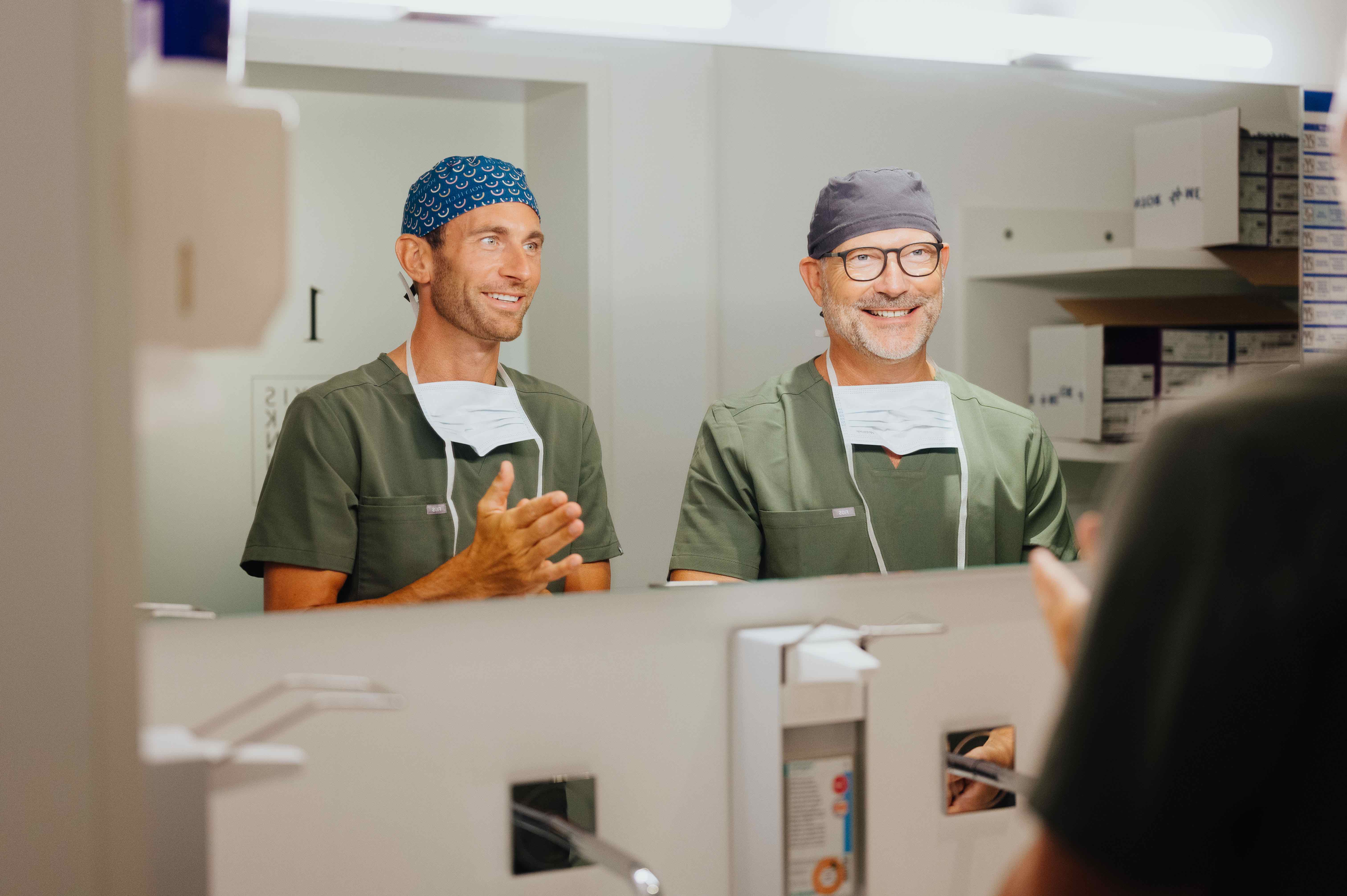 Dr. Bergmann und Dr. Kruess stehen nebeneinander vor dem Spiegel und unterhalten sich.isklinik - Colonnaden in Hamburg.