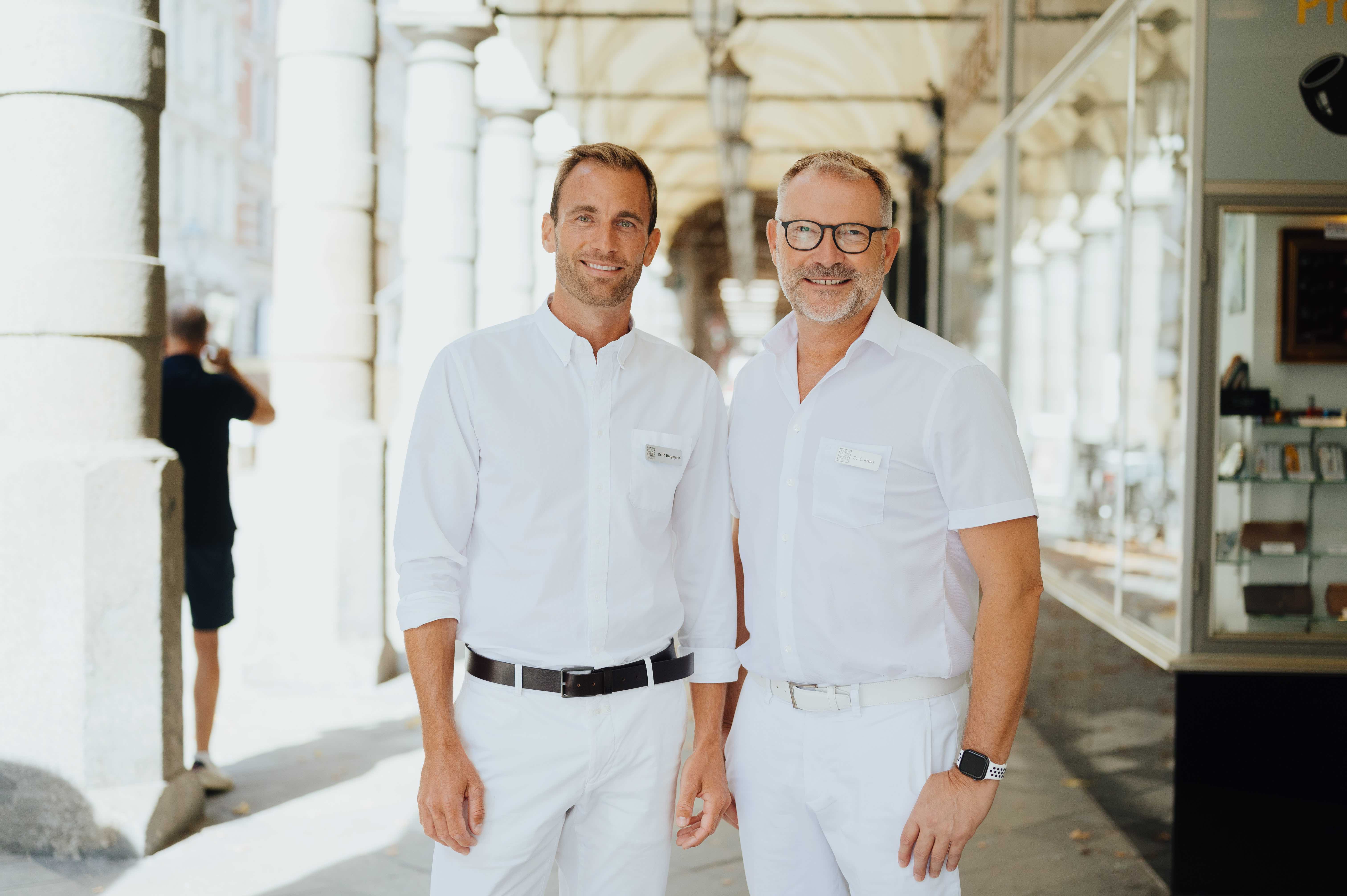 Dr. Bergmann und Dr. Kruess stehen nebeneinander vor der Praxisklinik - Colonnaden in Hamburg.