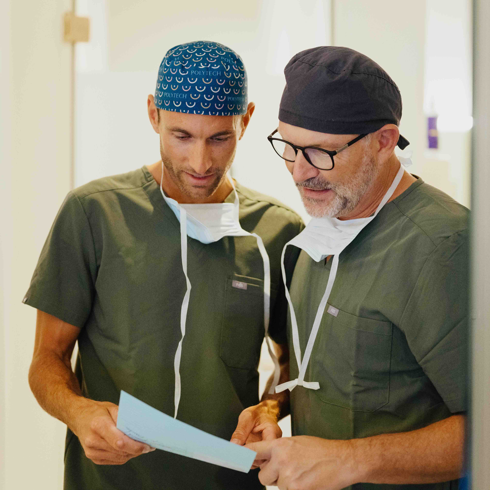 Dr. Bergmann und Dr. Kruess stehen nebeneinander und besprechen gemeinsam eine Patientenbehandlung.