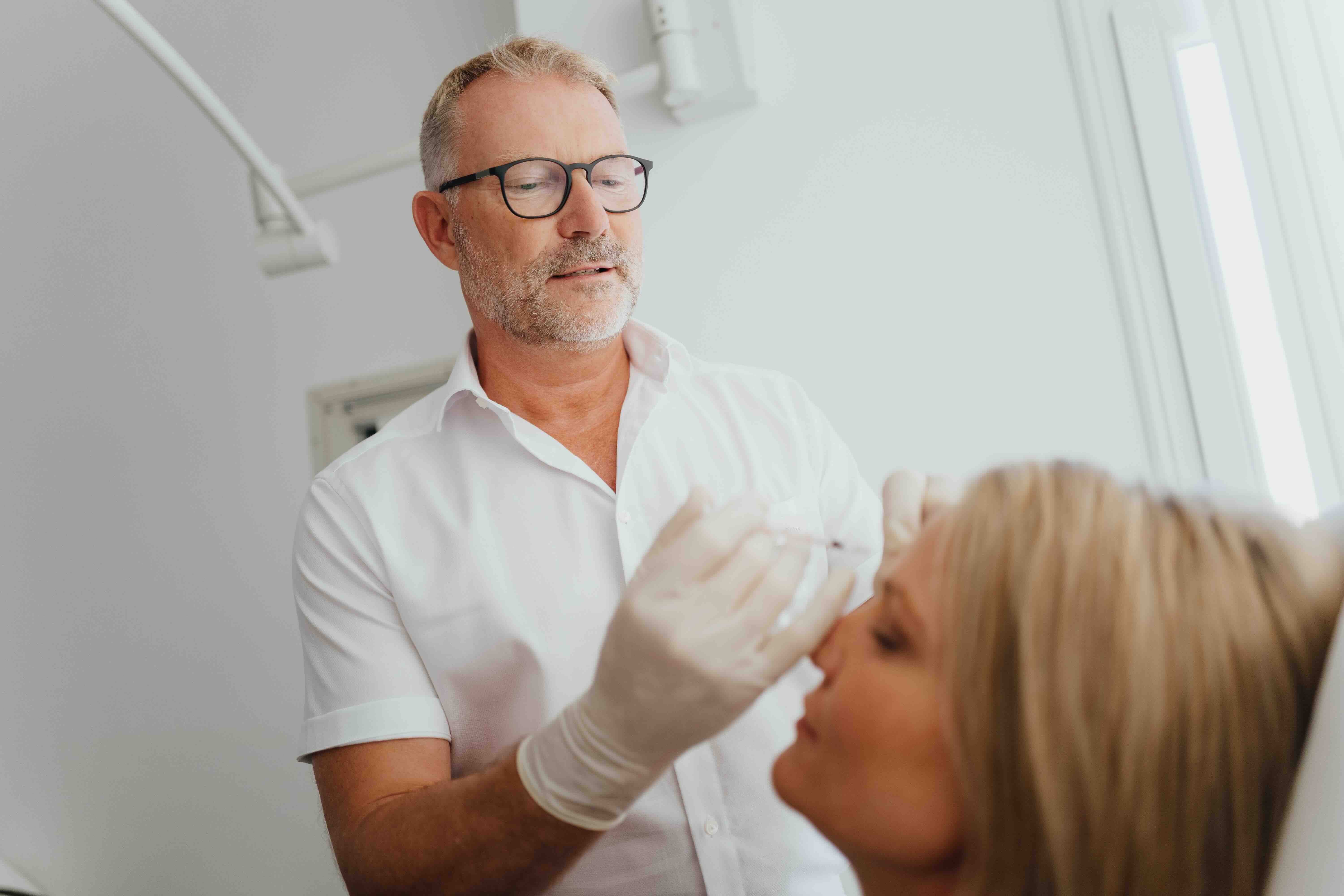 Dr. Kruess führt eine Faltenunterspritzung bei einem Patienten durch.