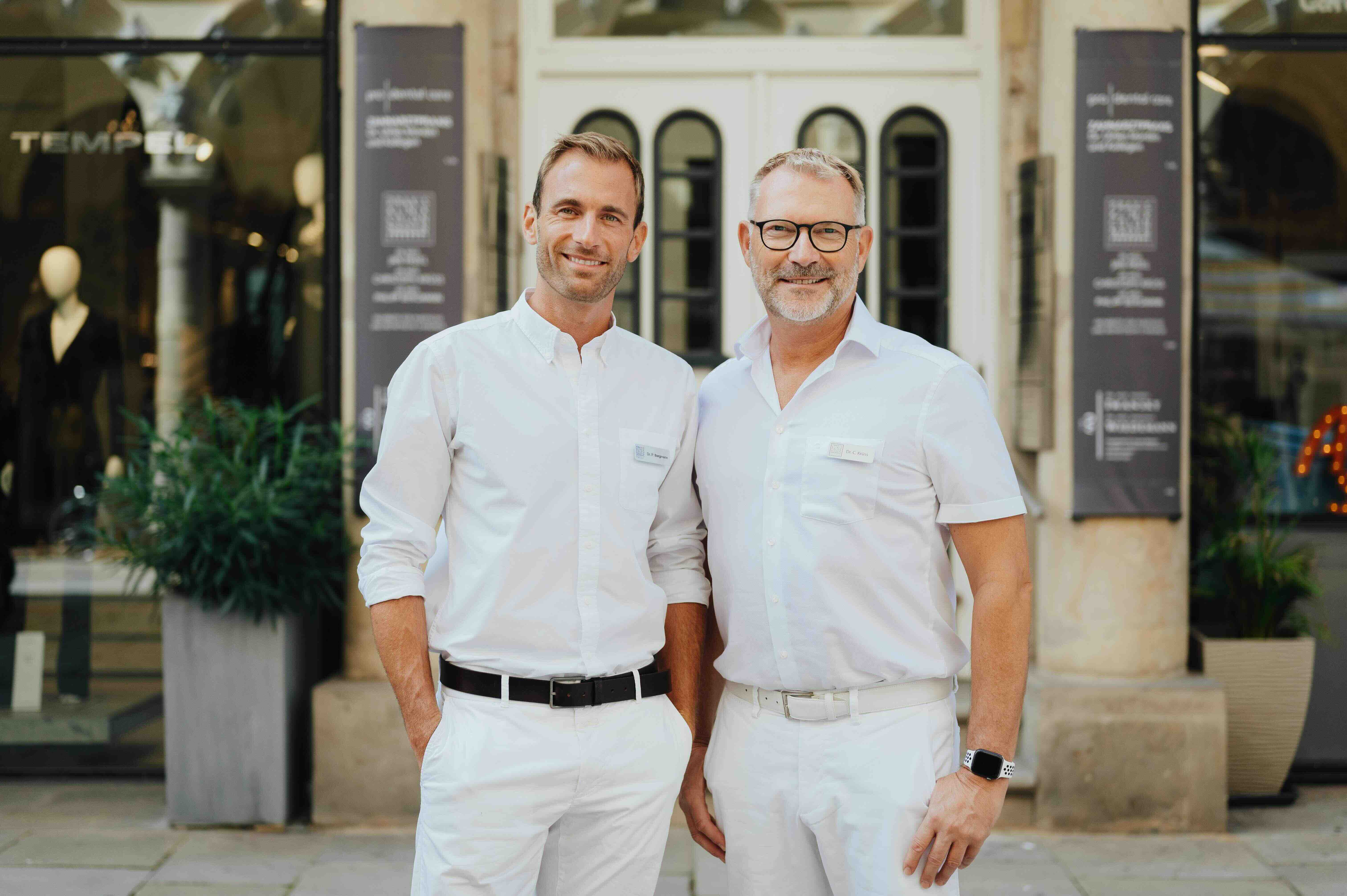 Dr. Bergmann und Dr. Kruess stehen nebeneinander vor der Praxisklinik - Colonnaden in Hamburg.